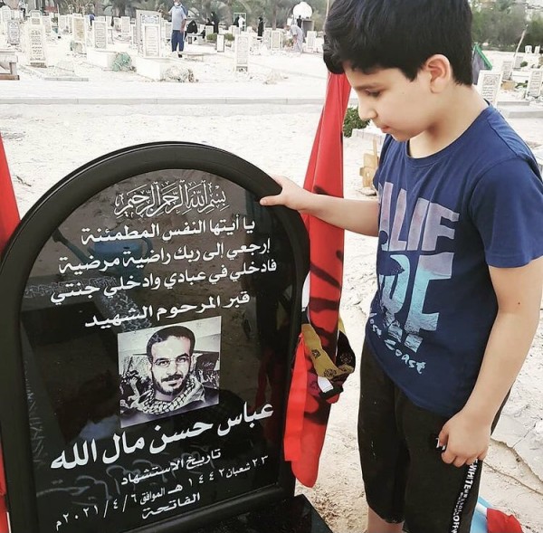 Martyr Abbas Malullah's son standing at his grave